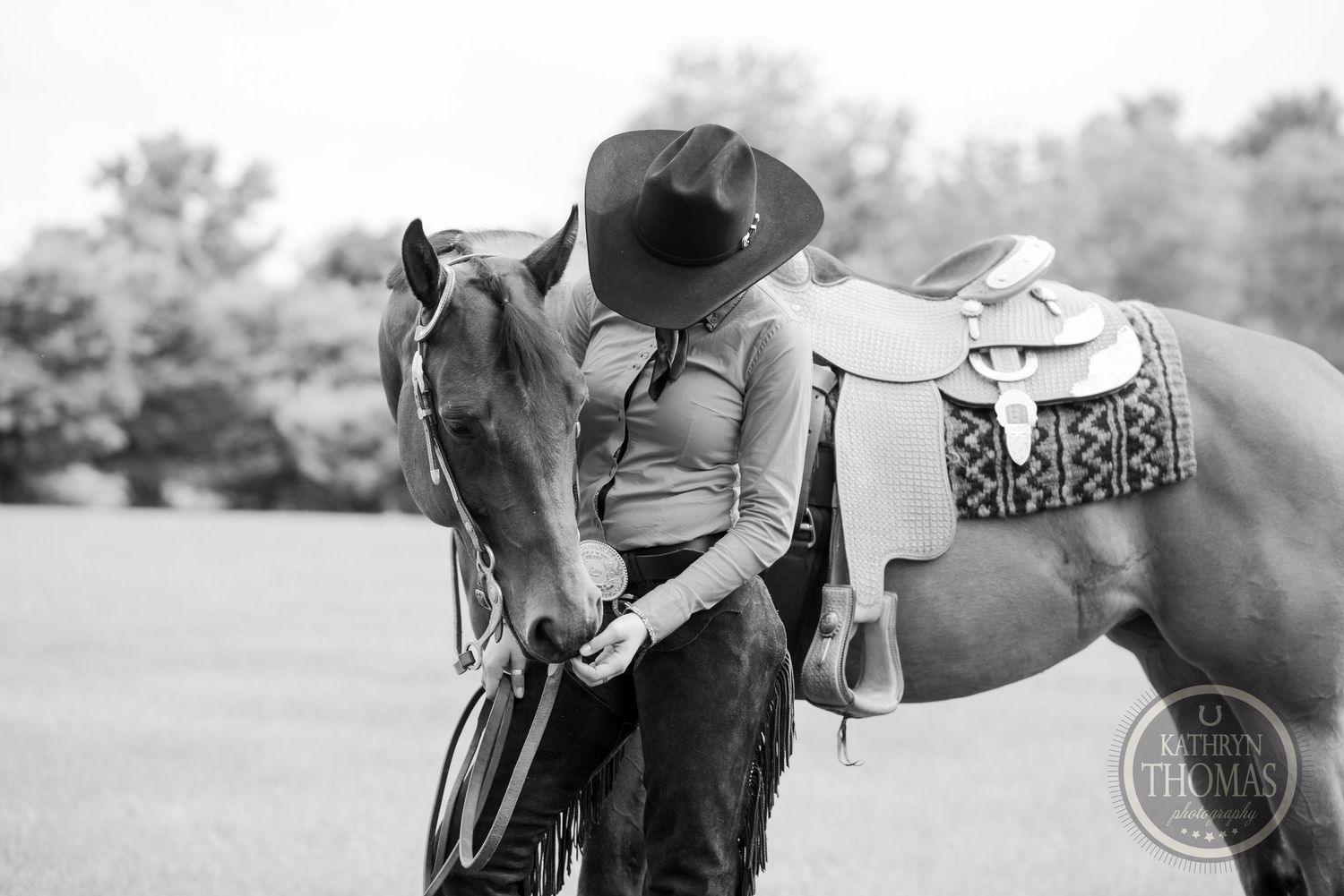Black and white photo of horse and rider sharing a tender moment with western tack.