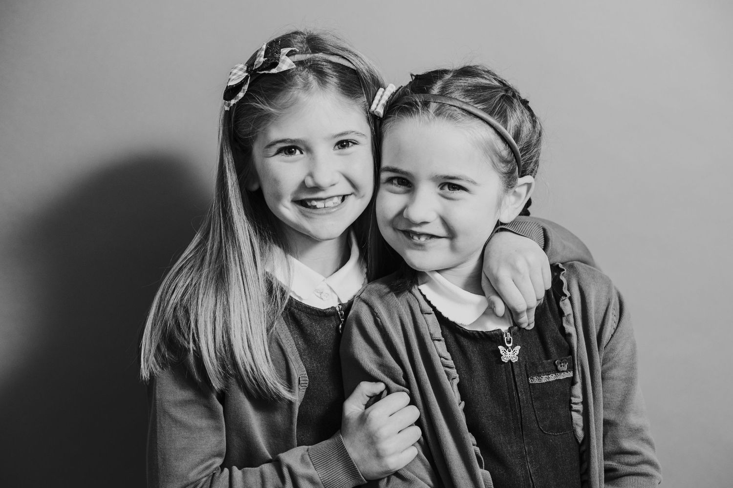Two young students in school uniforms share a friendly moment during portrait day.