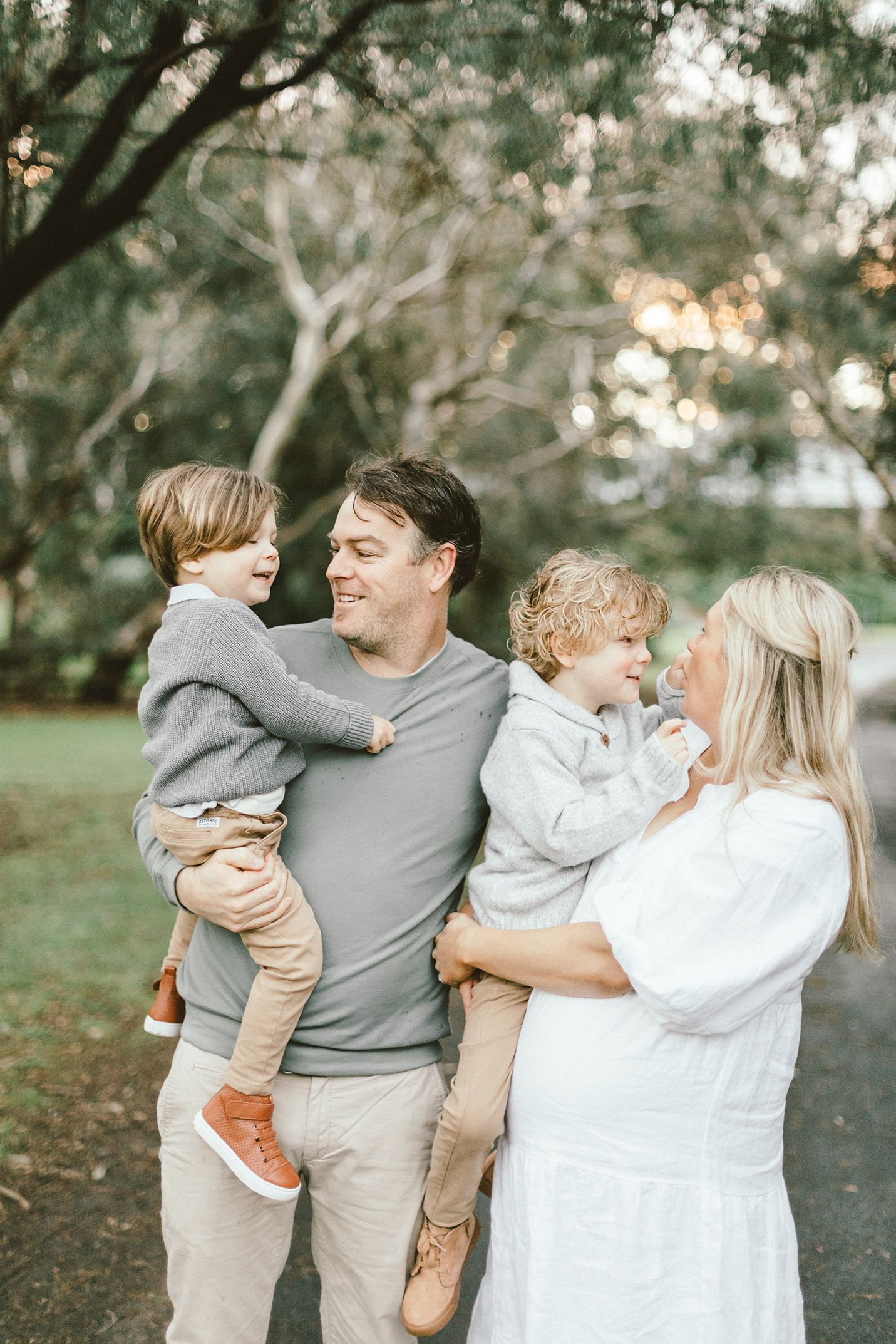 A tender family moment captured under eucalyptus trees at golden hour.