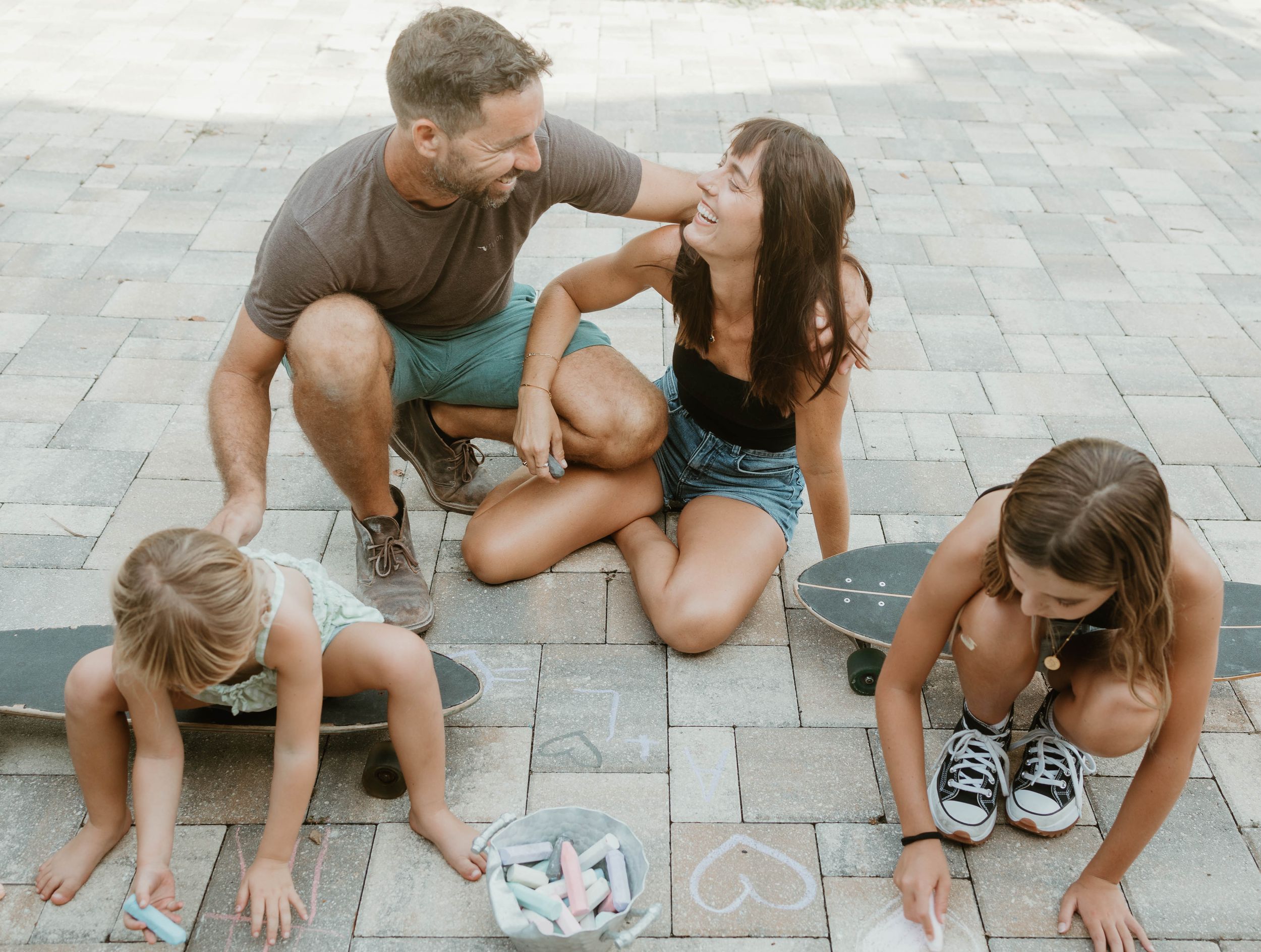 Playful sequence of people crouching and interacting on a paved outdoor surface.