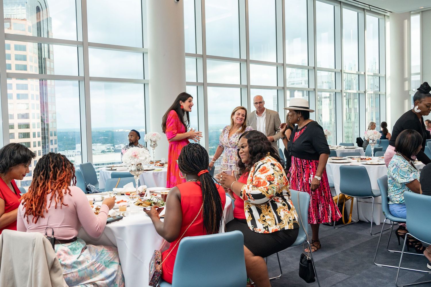 Modern dining room with floor-to-ceiling windows hosting a lively social gathering.