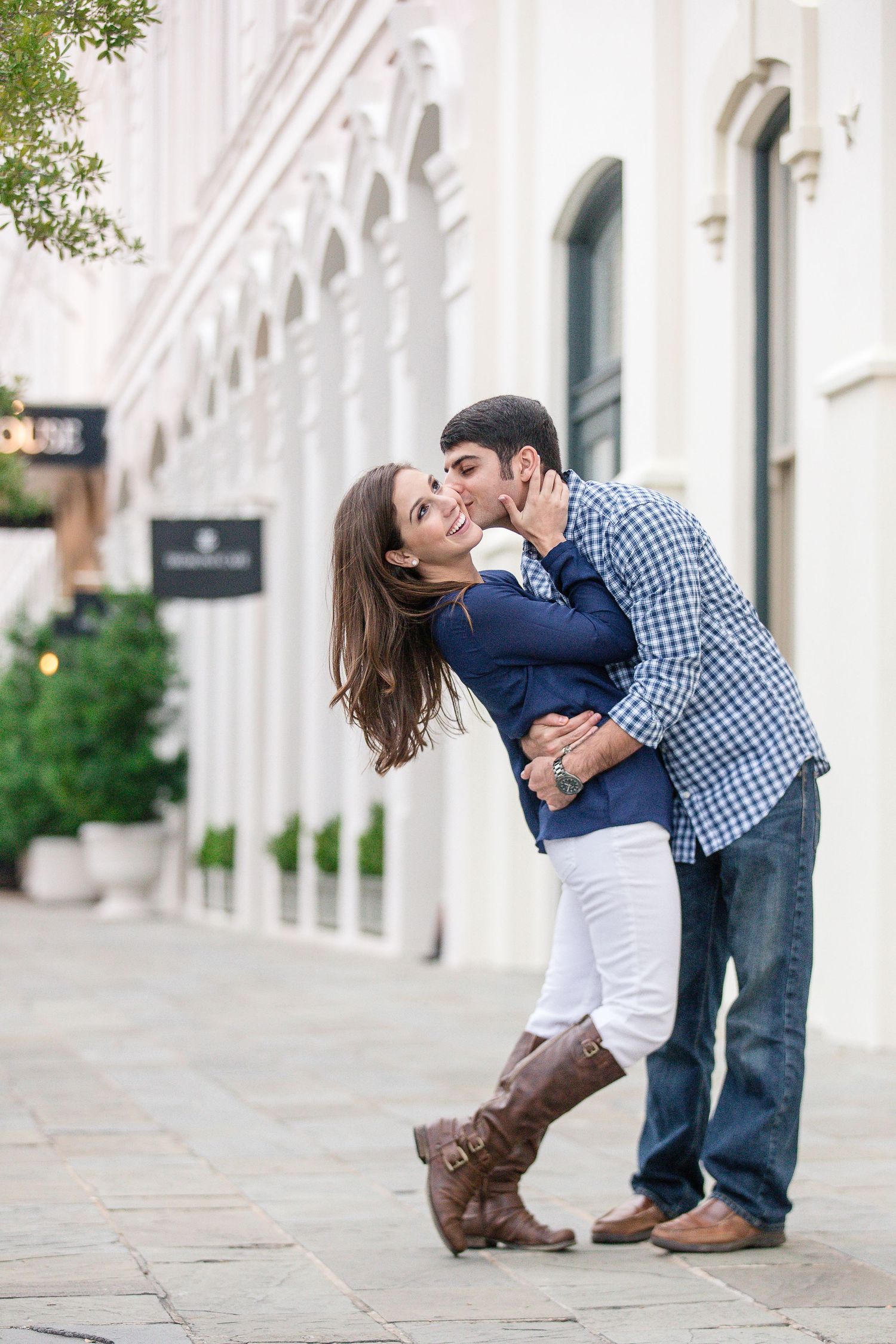 A couple shares a romantic dance pose in front of a white columned building.