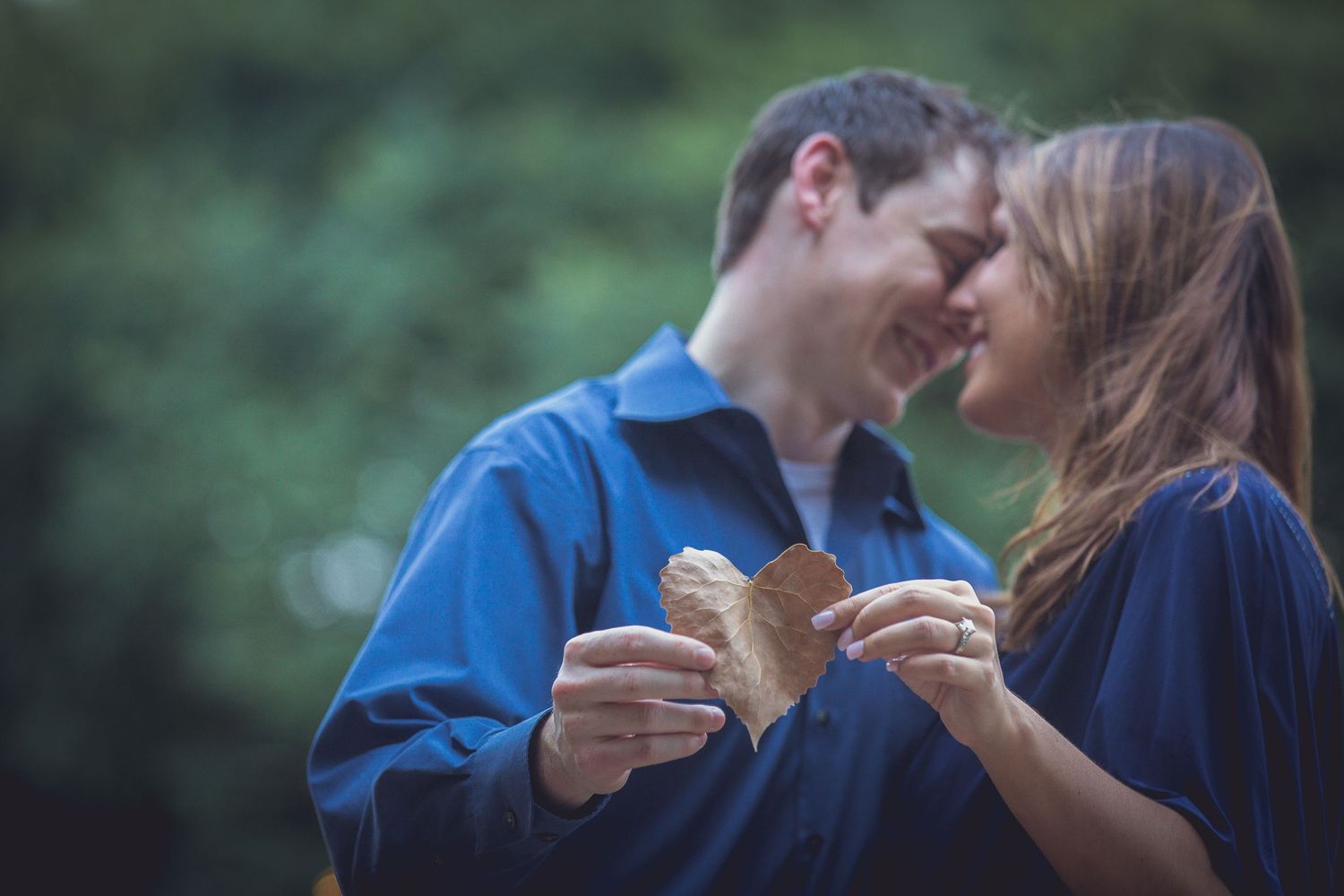 A couple in matching blue outfits shares a tender moment outdoors.