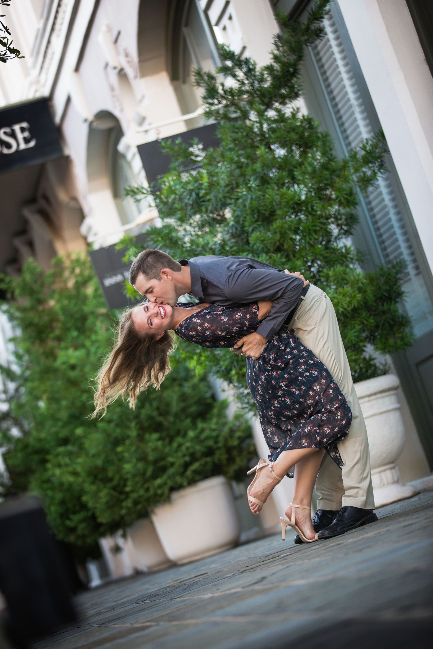 Dramatic dip pose in front of classic architecture with elegant styling.