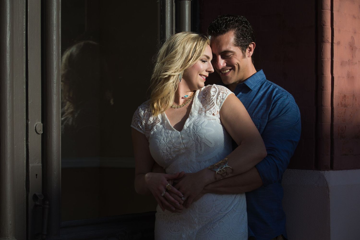 Dramatic shadows frame romantic couple against dark background.
