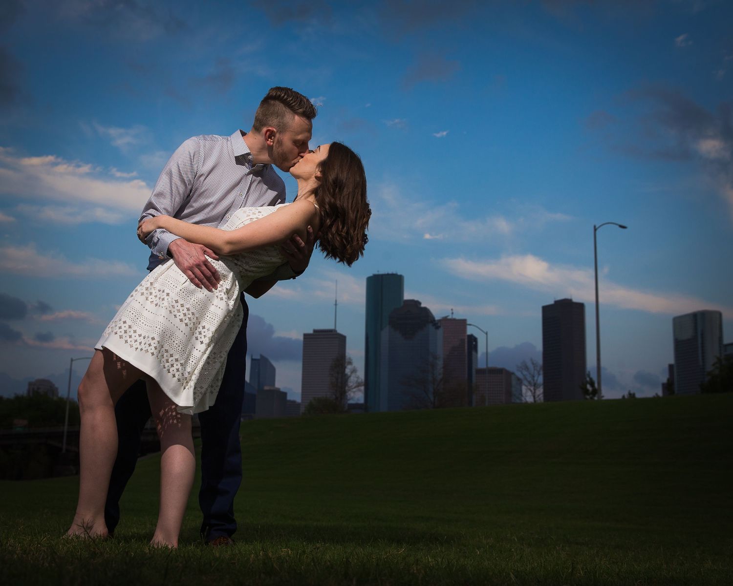 Romantic couple embraces against a dramatic city skyline at sunset.