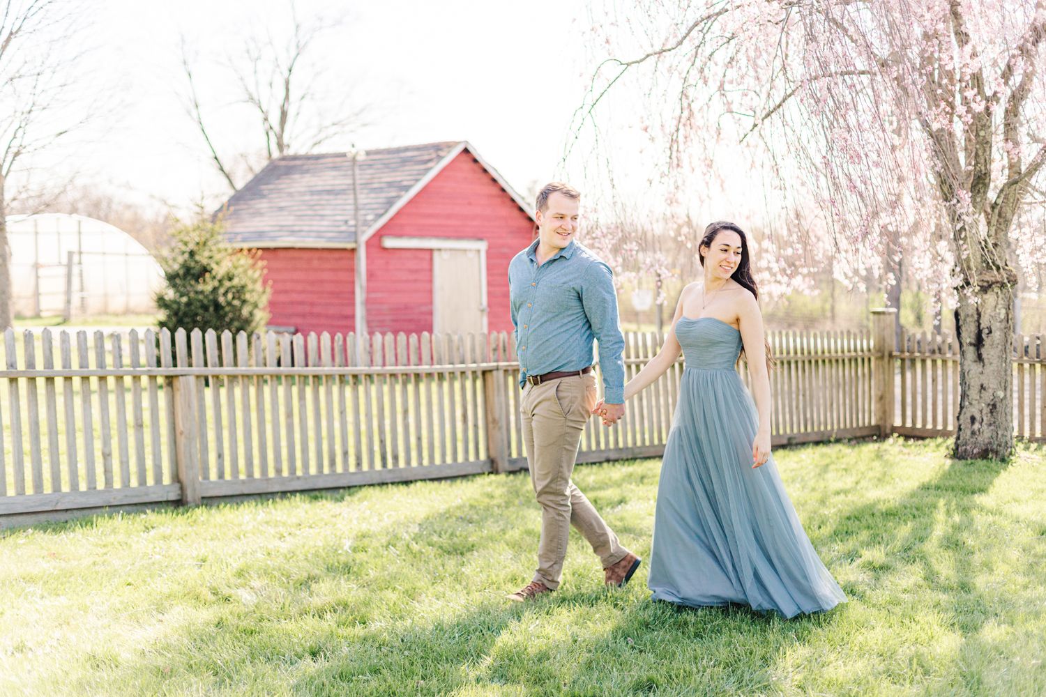 Couple in blue walking by fence and tree during session with Hudson Valley, NY photographer Danielle Lauren Photography