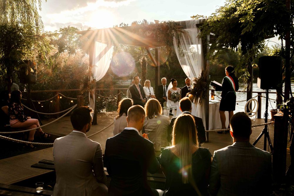 Outdoor wedding ceremony at sunset with flowing white curtains and natural backdrop.