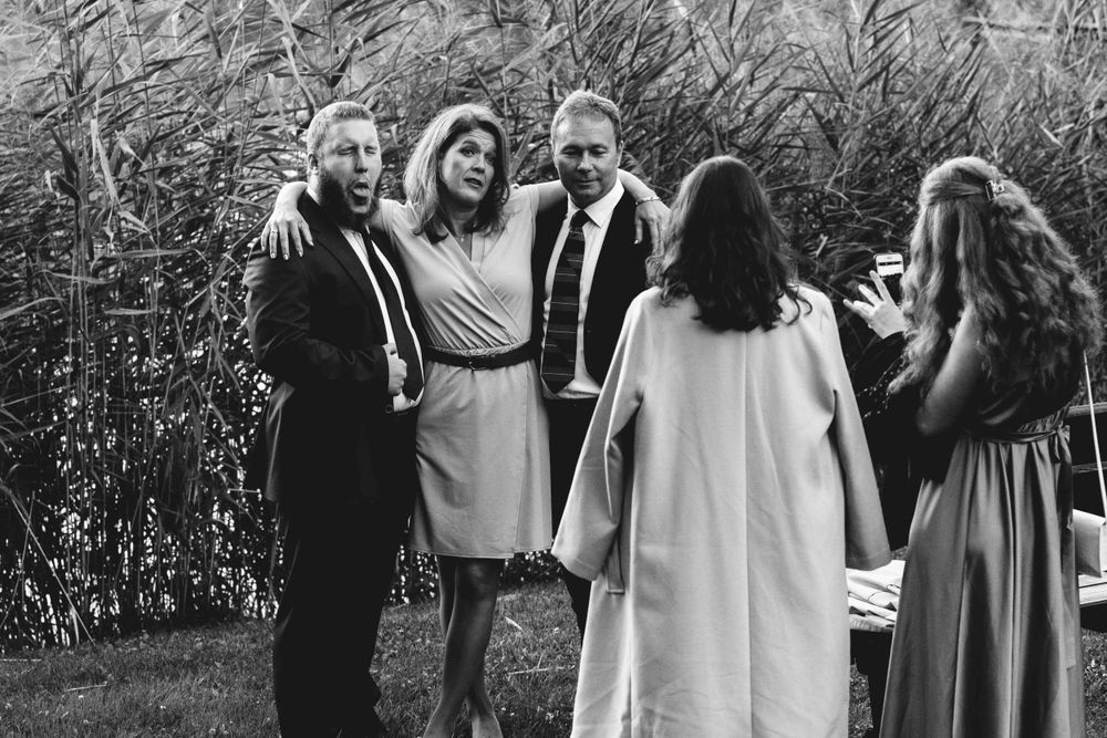 Black and white photo of wedding guests laughing together outdoors.