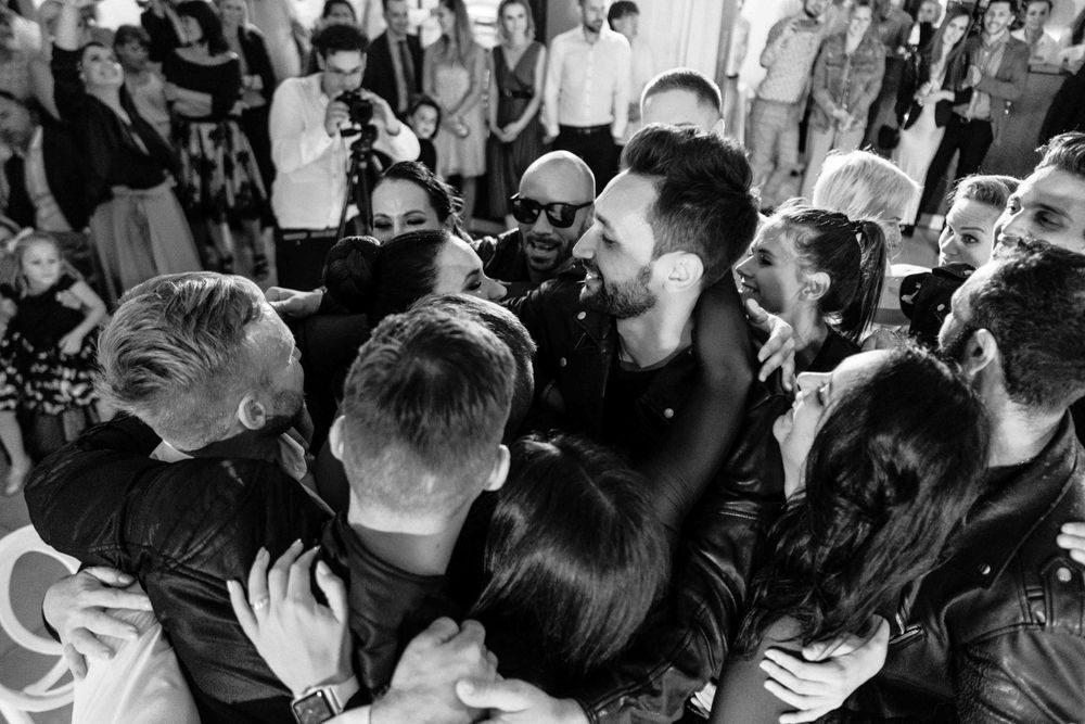 Black and white candid photo of wedding guests celebrating on dance floor.