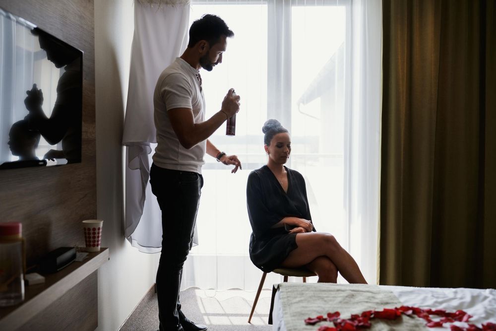 A behind-the-scenes moment during wedding preparations in a hotel room with soft window lighting.