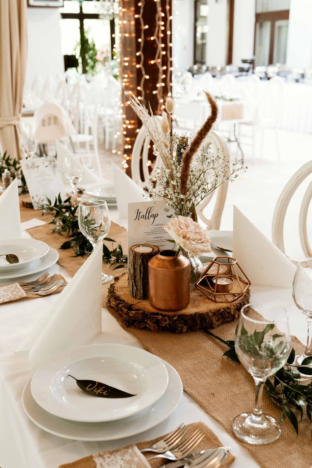 Rustic wedding table setting with wood slices, copper accents, and delicate floral arrangements.