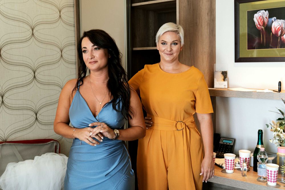 Bridesmaids in contrasting blue and yellow dresses stand together in a decorated room.
