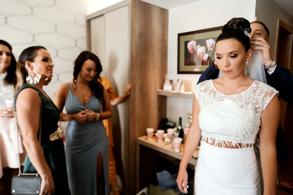 Pre-wedding preparation scene with attendants helping with final touches.
