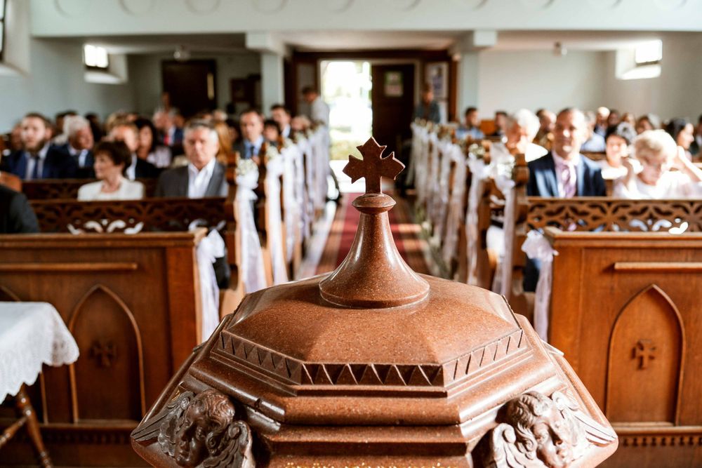 Ornate wooden church pulpit with carved details shown in a church filled with guests in the pews.