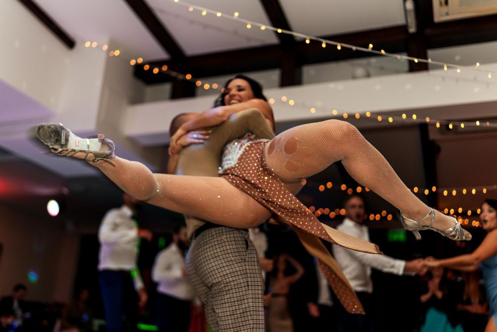 Dancers performing an impressive lift move during a dance performance under string lights.