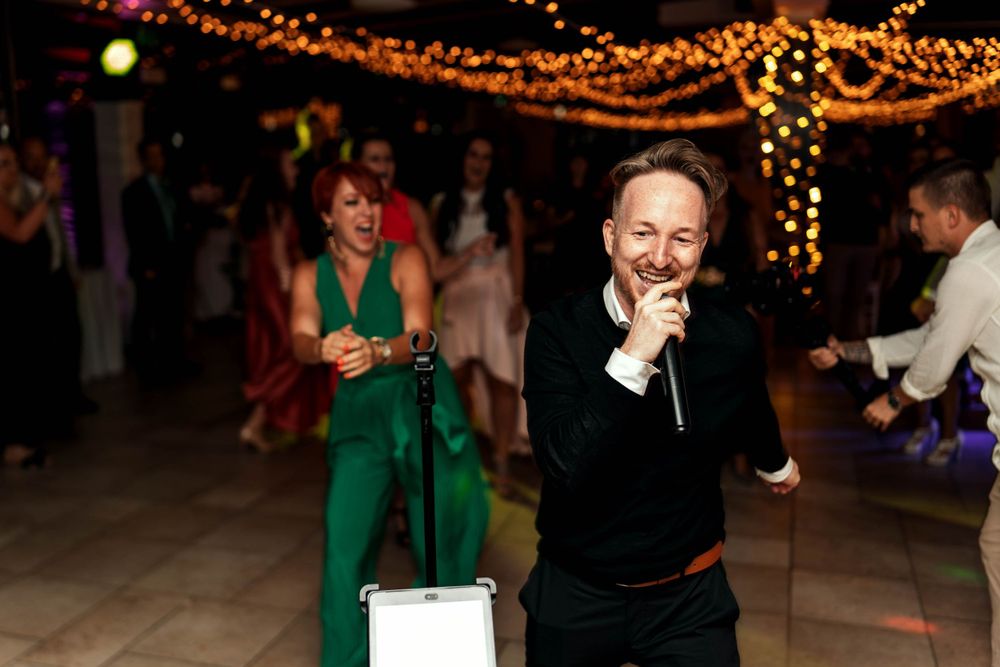 Party guests dancing under warm string lights at an indoor celebration.