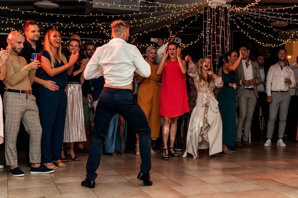 People dancing at a wedding reception under strings of twinkling lights.
