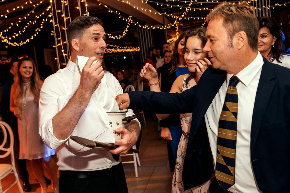 Wedding guests sharing dessert during reception under string lights.