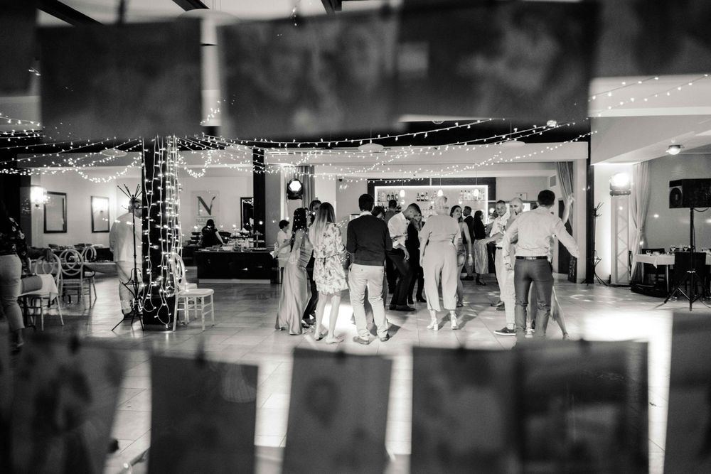 Black and white photo of people dancing at a party in a decorated indoor venue.