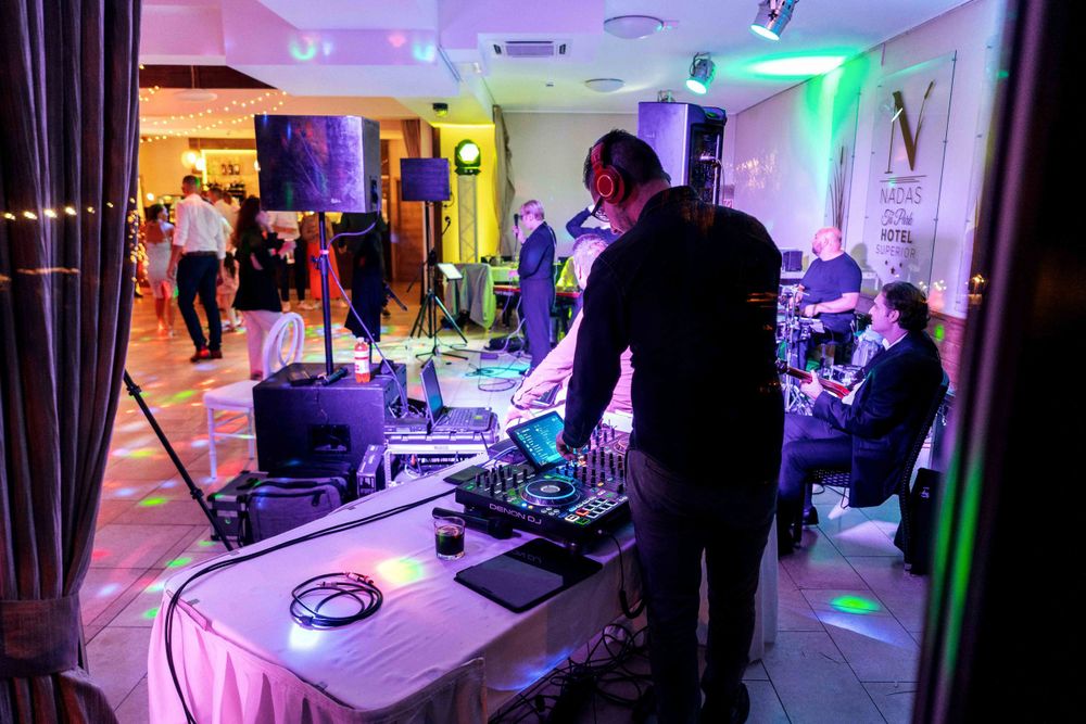 DJ performing at a nightclub with colorful lighting and sound equipment.