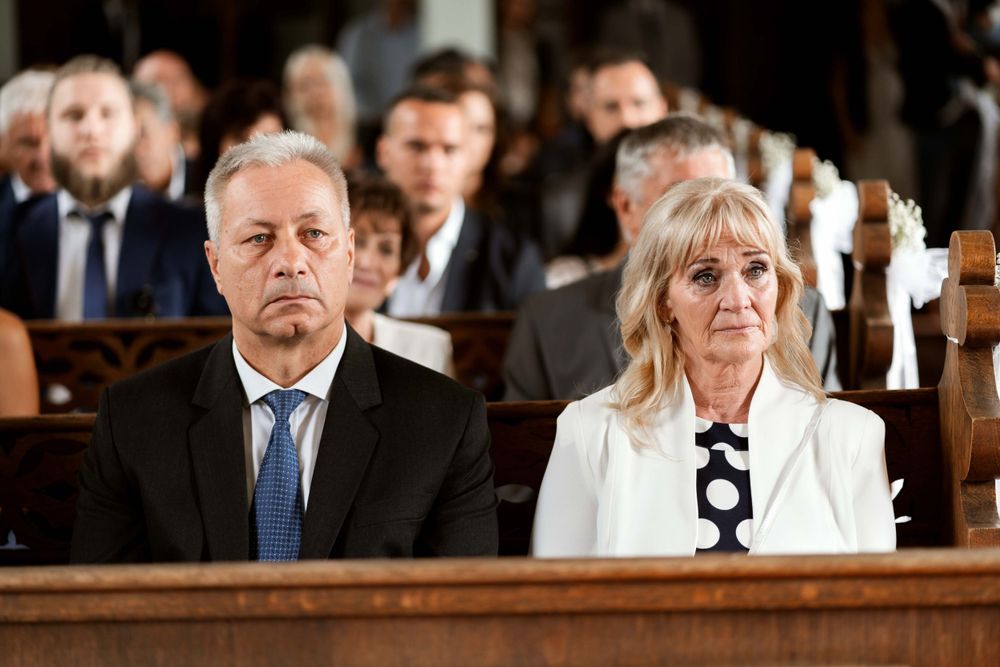 Guests seated in wooden church pews during formal wedding ceremony.
