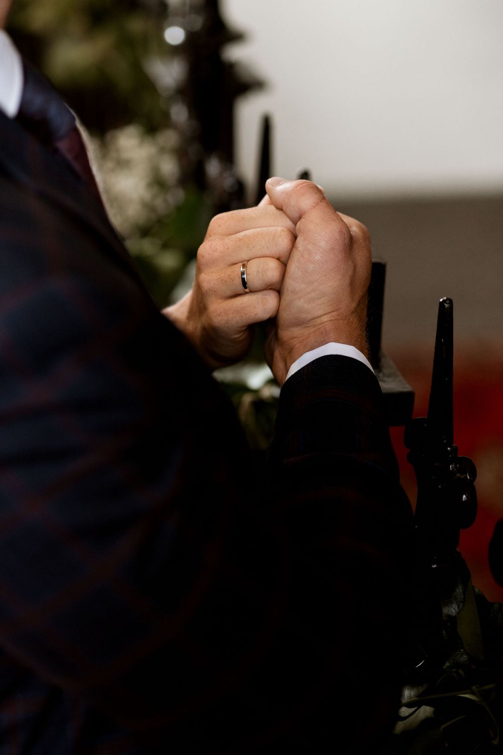 A close-up shot of clasped hands with a wedding ring during a ceremony.