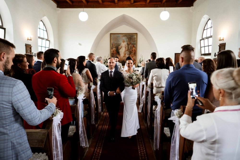 Wedding guests taking photos in a church aisle during a ceremony.