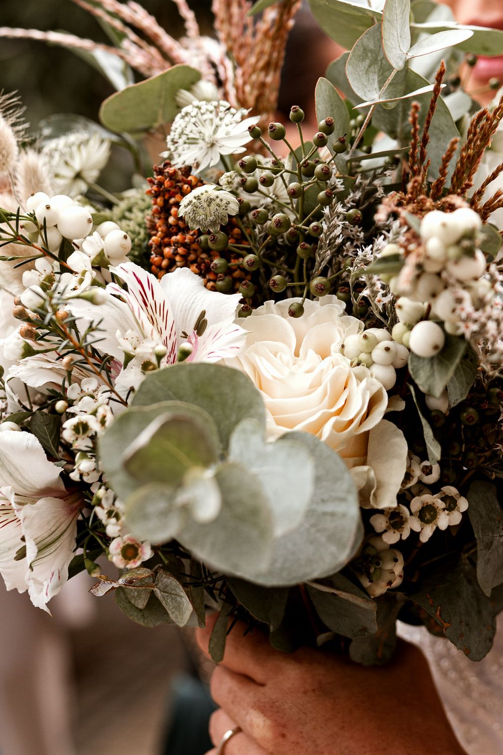 An elegant wedding bouquet with roses, eucalyptus, and dried flowers in neutral tones.