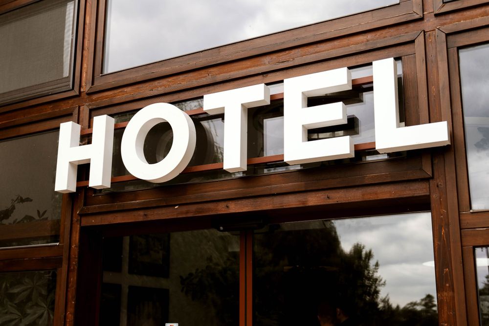 White HOTEL lettering mounted on a wooden and glass exterior wall.
