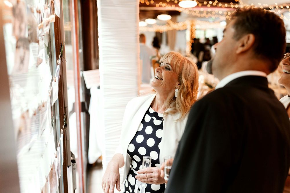 Wedding guests admire artwork on display at an elegant indoor venue.