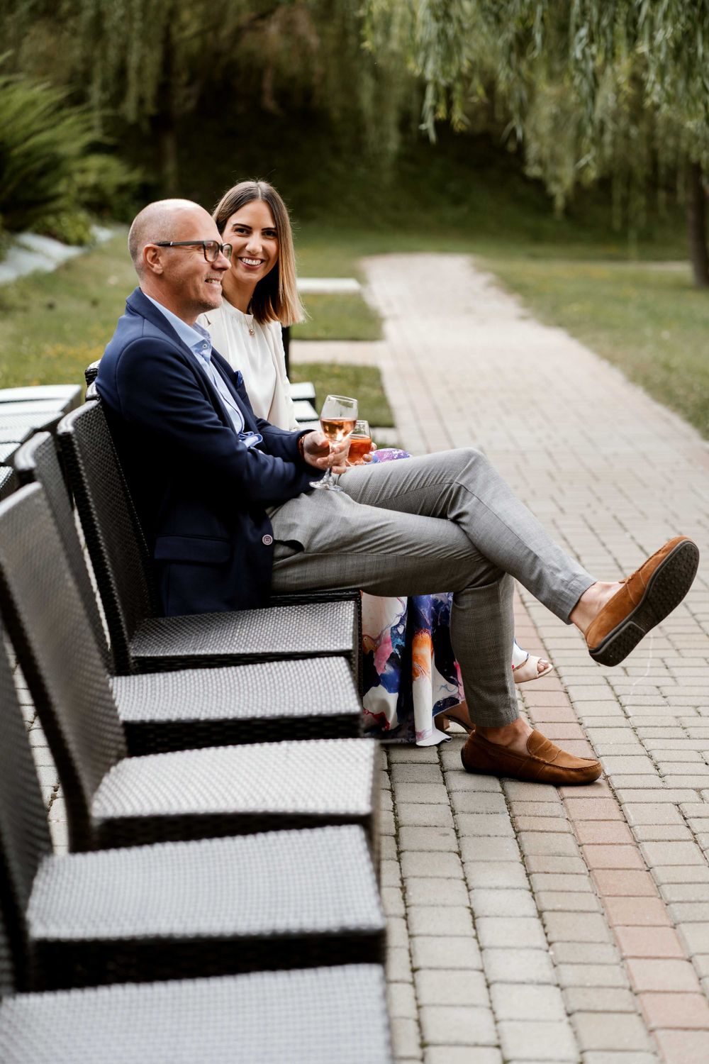 Two people relax on outdoor patio furniture during a wedding celebration.