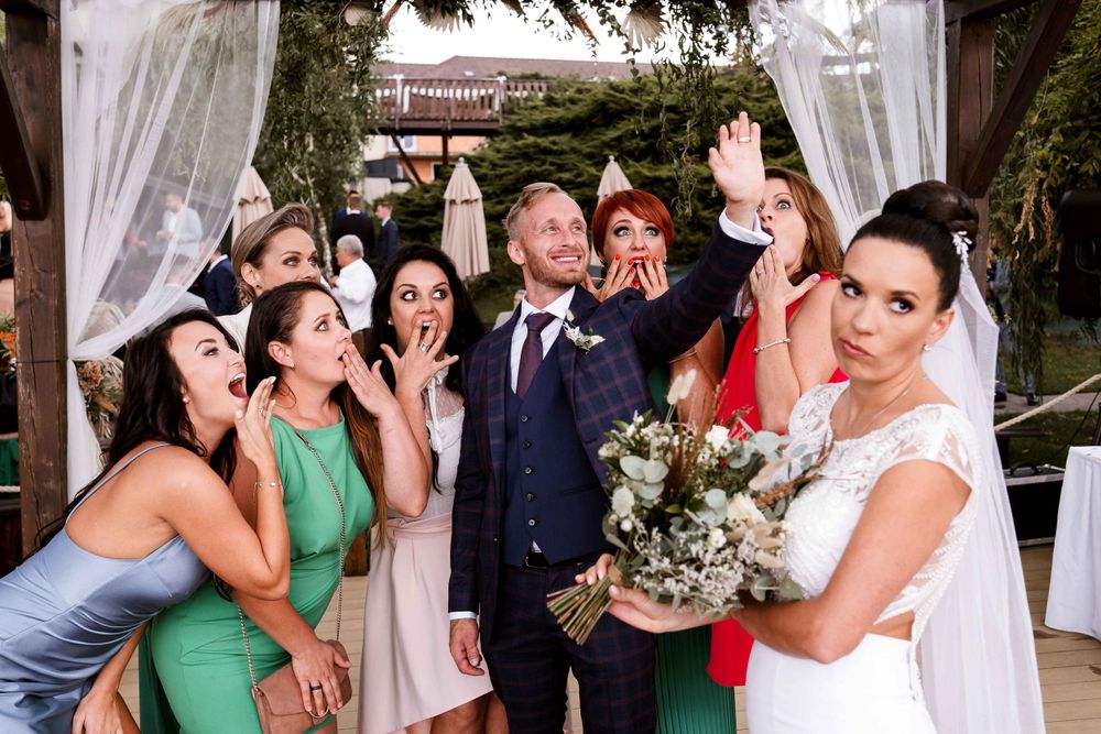 Wedding party poses for fun group photo with surprised expressions.