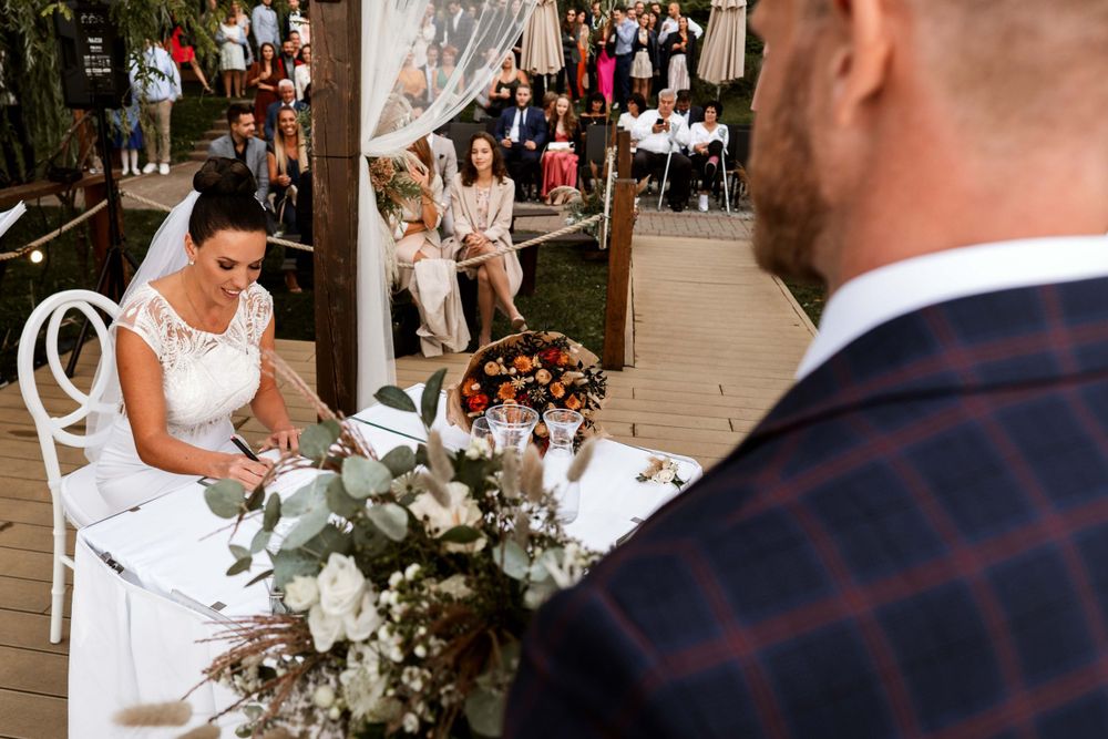 Intimate outdoor wedding ceremony with white floral decorations and wooden pergola.