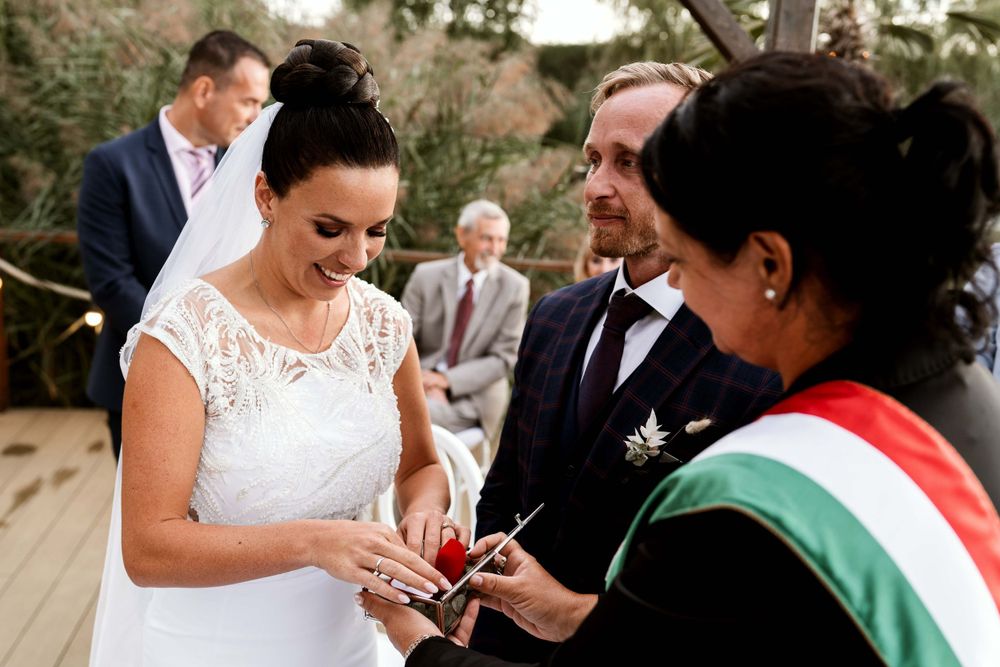 Wedding ceremony with official wearing tricolor sash during ring exchange.