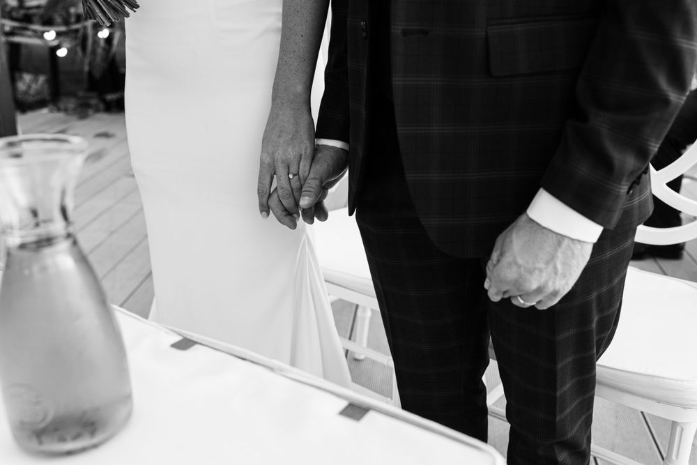 Black and white detail of wedding couple standing at decorated table.
