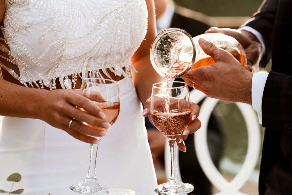 Pouring champagne into glasses at outdoor wedding celebration.