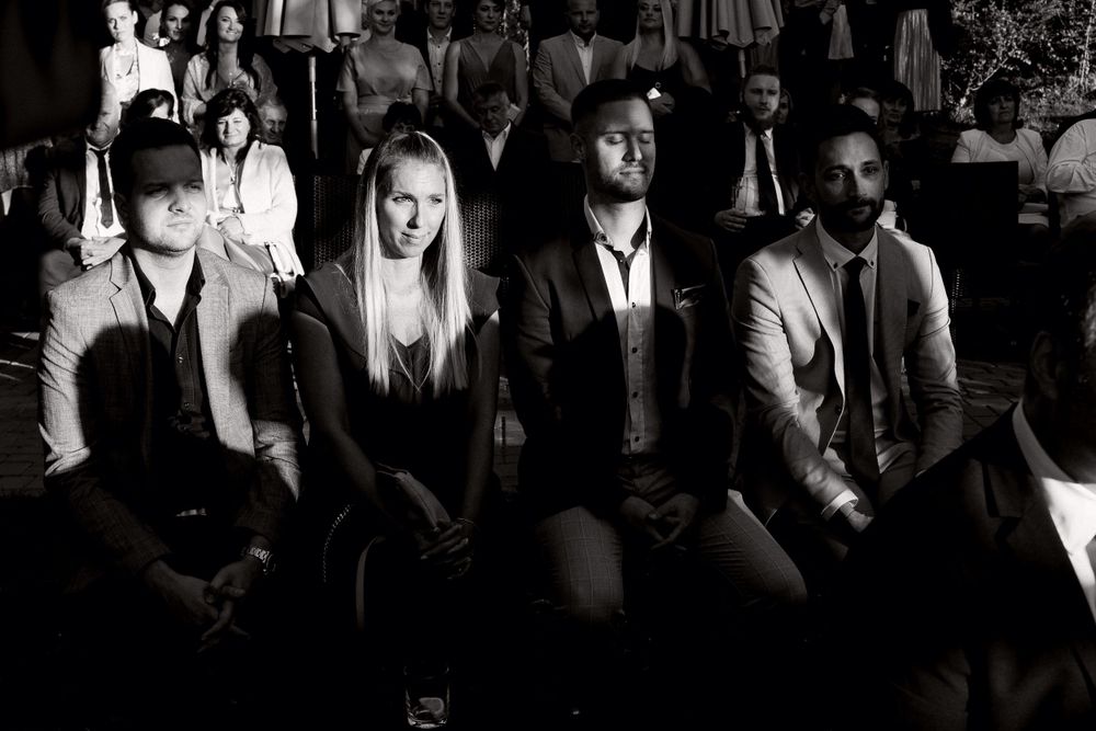 A black and white photo showing guests seated in formal attire at a front row of an event.