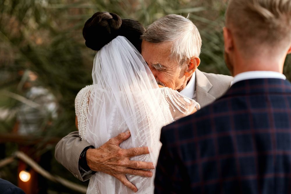 An emotional embrace is shared during an outdoor wedding ceremony.