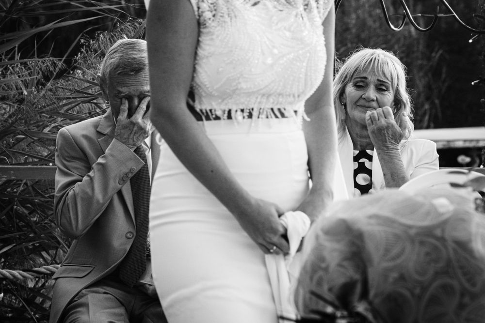 Black and white candid moment at outdoor wedding with guests reacting.
