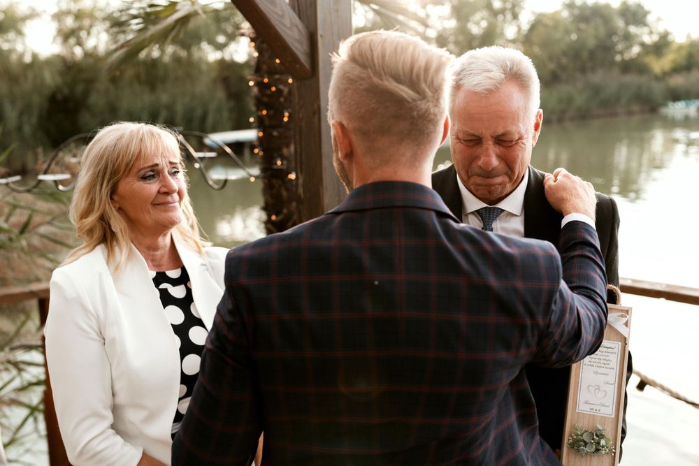 An intimate wedding ceremony moment captured at sunset by a waterfront venue.