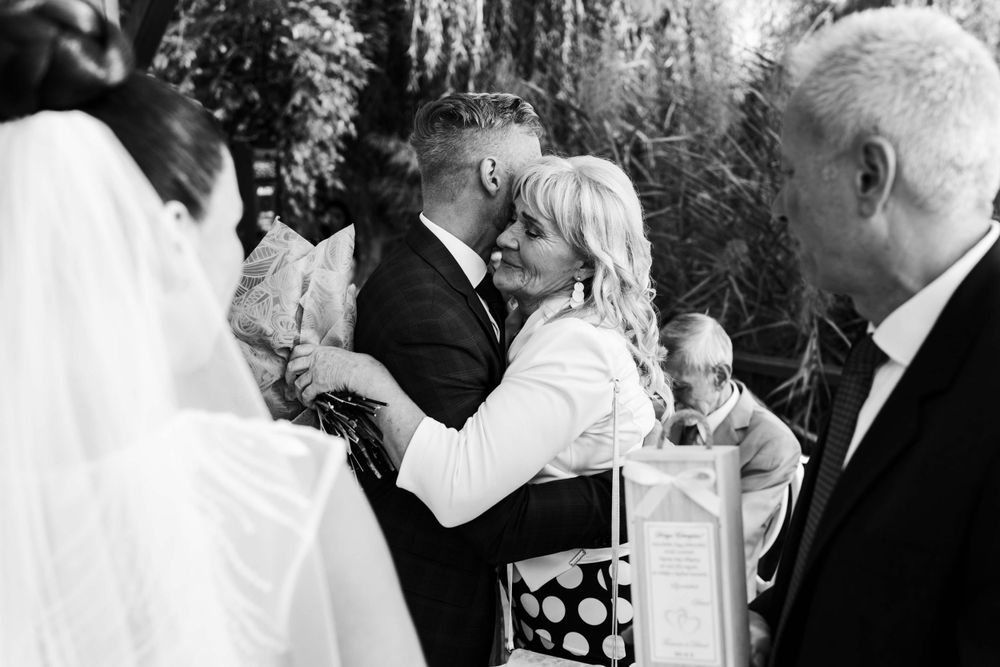 A black and white capture of intimate moments during an outdoor wedding celebration.