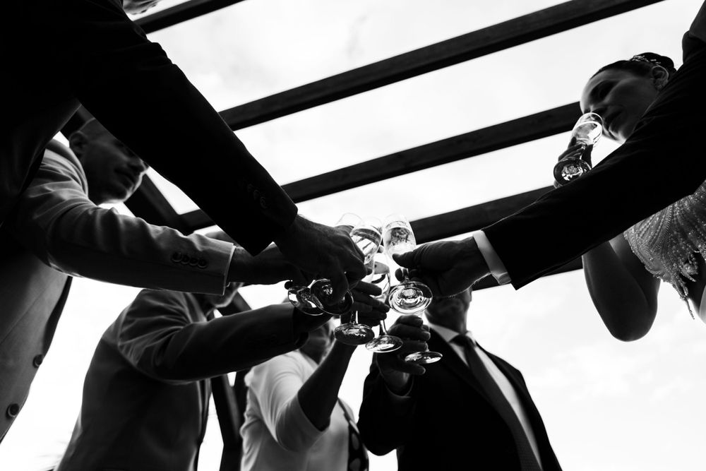 A dramatic black and white photo of hands toasting with champagne glasses.