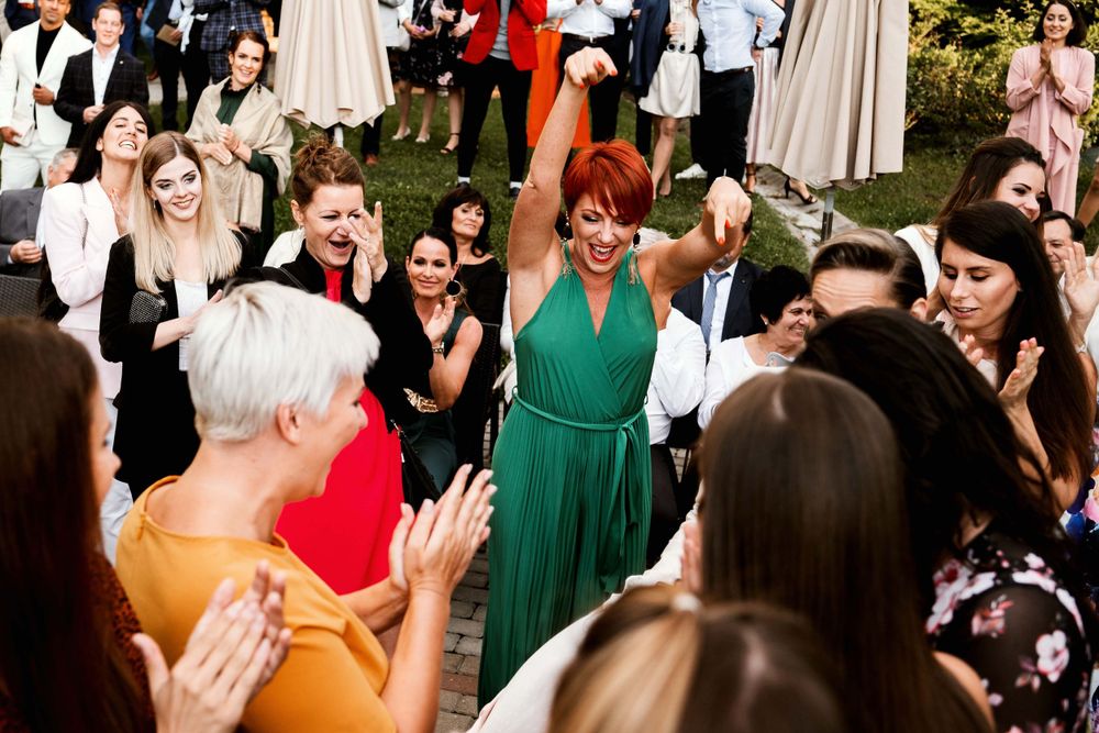 Wedding guests celebrate on a dance floor during an outdoor reception.