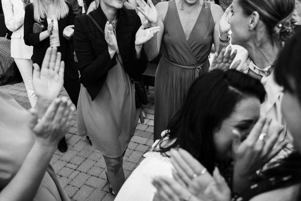 Black and white photo of wedding guests dancing and clapping at a reception.