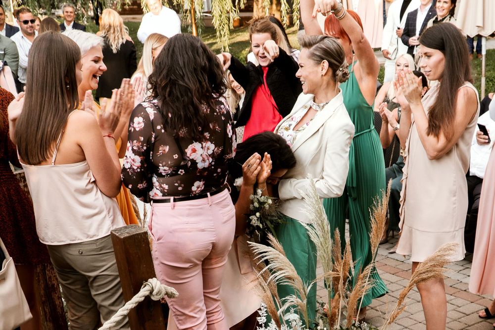 A group of wedding guests dancing and celebrating joyfully at an outdoor reception party.