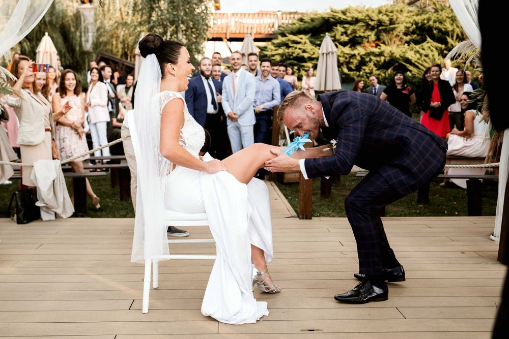 A wedding tradition being performed with guests seated outdoors under a covered patio area.