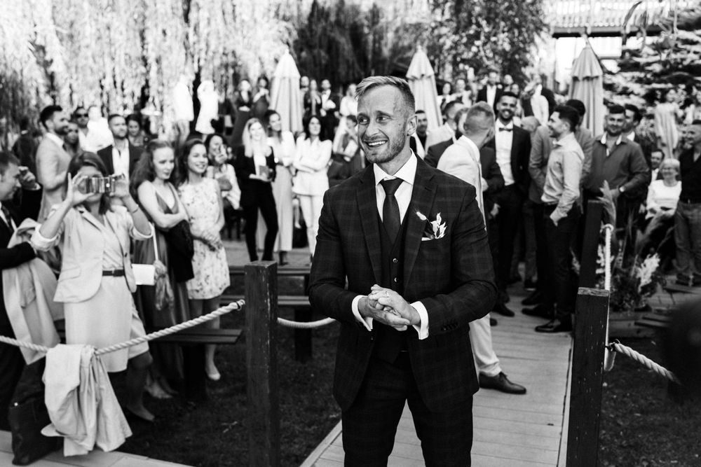 A black and white photo of a wedding celebration with guests in the background.