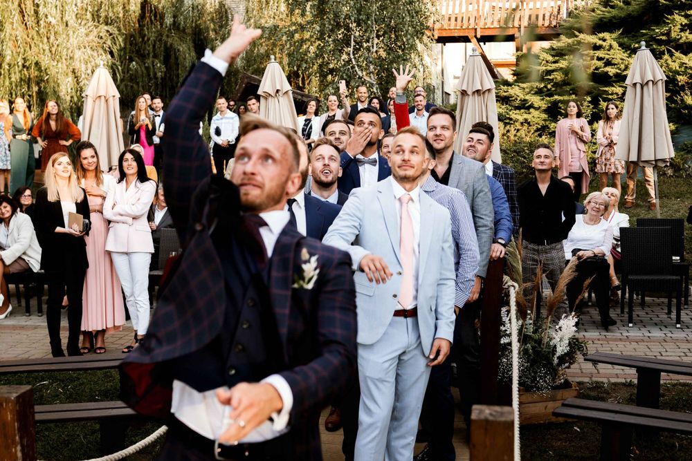Wedding guests celebrating during an outdoor reception under willow trees.