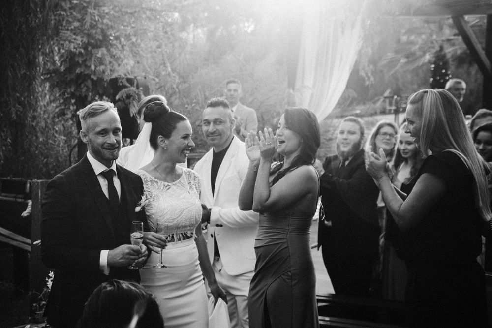 A black and white photo of wedding guests mingling during an outdoor celebration.